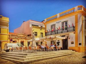 Un groupe de personnes assises à une table à l'extérieur d'un bâtiment dans l'établissement Origens Hostel, à Sines