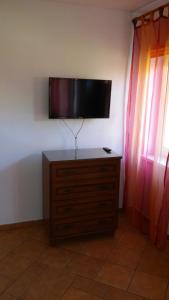 a flat screen tv on a wall with a dresser at Argo Domki in Darłowo