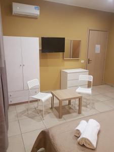 カターニアにあるCasa Serenaのキッチン(白い家具、テーブル、椅子付)