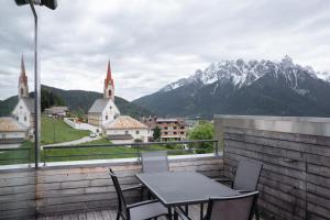 einen Tisch und Stühle auf einem Balkon mit Bergblick in der Unterkunft Appartement Hell in Toblach