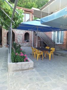 a patio with a table and chairs and a blue umbrella at Tsminda Giorgi Apartment in Sighnaghi