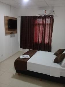 a bedroom with a bed and a window with a television at Porto Seguro Office Hotel in Bauru +19 photos
