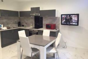 a kitchen with a table and white chairs in it at LesJardinsFleuris in Mandelieu-La Napoule
