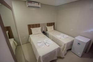ジュアゼイロ・ド・ノルテにあるHotel Encosta do Hortoのベッド2台と冷蔵庫が備わる客室です。