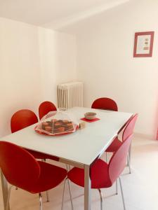 uma mesa branca com cadeiras vermelhas e um prato sobre ela em Dimora del cuore em Tirano
