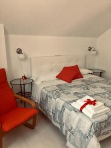 um quarto com uma cama e uma cadeira vermelha em Dimora del cuore em Tirano