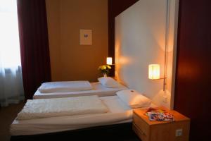 a hotel room with two beds and a table at Hotel Columbus in Frankfurt/Main