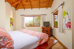 a bedroom with a bed and a tv and a window at Los Altos de Eros - Adults Only in Playa Avellana