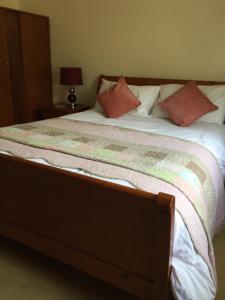 Una cama con sábanas blancas y almohadas rosas. en Shore Road Enniskillen, en Enniskillen