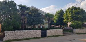 Casa blanca con una valla de piedra y árboles en Apartment Jadranka, en Zadar