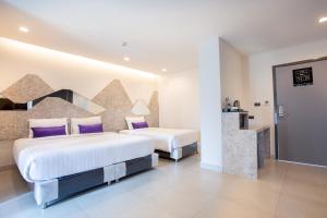 Habitación de hotel con 2 camas con almohadas moradas en Spittze Hotel Pratunam, en Bangkok