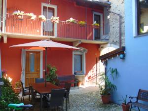 a table with an umbrella in front of a building at Hortus Lake Orta in Omegna