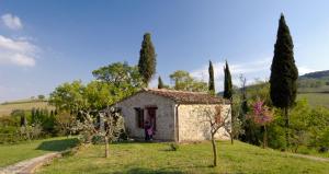 um pequeno edifício de pedra num campo com árvores em Podere Montese Country House em San Gimignano