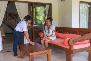 deux femmes debout dans un salon avec une table dans l'établissement Villa Gayatri Hidden Oasis, à Amed 31 autres photos