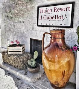 un grande vaso seduto di fronte a un cartello di Tipico Resort ad Alberobello