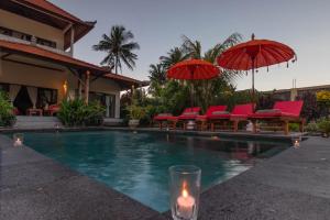 - une piscine avec des chaises rouges, des parasols et une bougie dans l'établissement Villa Gayatri Hidden Oasis, à Amed