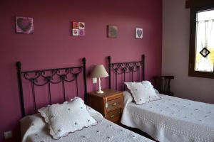 2 camas en un dormitorio con paredes moradas en Casa Rural Casa Jacinta, en San Cristóbal de Segovia