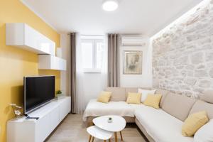 a living room with a white couch and a tv at House RokaStone in Split