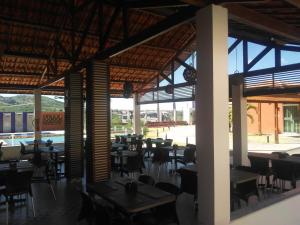 ein Restaurant mit Tischen und Stühlen und einem Pool in der Unterkunft Hotel Encosta do Horto in Juazeiro do Norte