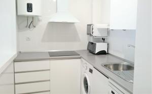 a white kitchen with a sink and a microwave at Apartamento de dos dormitorios junto a Mojácar Playa in Garrucha