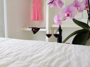 a bed with two glasses of red wine and flowers at Anita Rooms & Apartments in Adamantas
