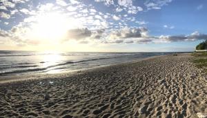 a sandy beach with the sun rising over the ocean at Studio Bis Cocoon in Saint-Gilles les Bains