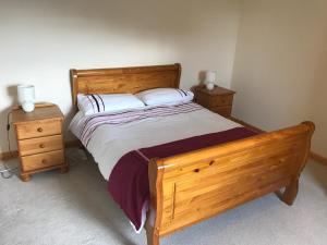 a bedroom with a wooden bed with two night stands at 14 Upper Bayble in Stornoway