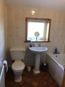 ein Bad mit einem WC, einem Waschbecken und einem Fenster in der Unterkunft 14 Upper Bayble in Stornoway
