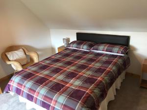 a bedroom with a bed with a plaid blanket at 14 Upper Bayble in Stornoway +2 photos