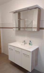 La salle de bains blanche est pourvue d'un lavabo et d'un miroir. dans l'établissement Ferienwohnung Berger, à Reinhardtsdorf