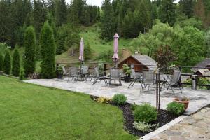 a patio with chairs and umbrellas in a yard at Clematis House in Voronet