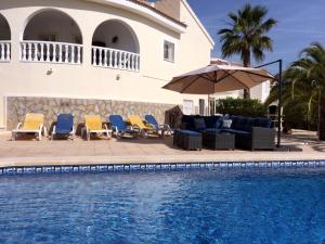 a pool with chairs and an umbrella next to a house at Casa Sara - Private Villa with Private Pool in Ciudad Quesada