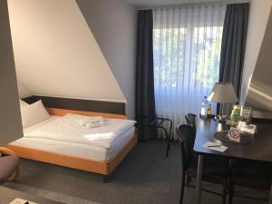 ein Hotelzimmer mit einem Bett, einem Schreibtisch und einem Fenster in der Unterkunft Apartment 47 in Sindelfingen