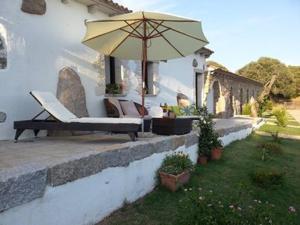 un patio con banco y sombrilla en B&B L' Incantu, en Santa Teresa Gallura