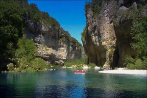 a red boat in a river next to a mountain at Gite Montalies in Novis