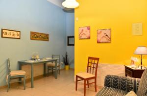 una sala de espera con mesa, sillas y una pared amarilla en Fiori e Coccole, en Noto