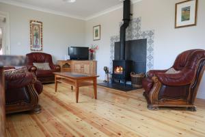 een woonkamer met lederen stoelen en een open haard bij Alices Loft & Cottages in Castleblayney