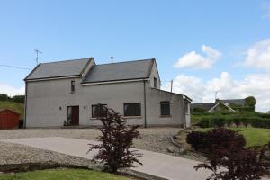 a large white house with a driveway at Alices Loft & Cottages in Castleblayney