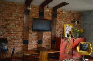 Mystic River Design Hostel في باغينا باستا: غرفة معيشة مع جدار من الطوب وتلفزيون
