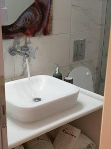a white sink in a bathroom with a toilet at Katerina Apartments & Studios in Naousa
