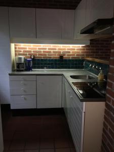 a kitchen with white cabinets and a brick wall at 't Aarthuis in Emst