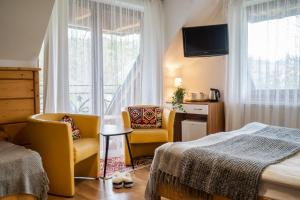 ein Schlafzimmer mit 2 Stühlen, einem Bett und einem Fenster in der Unterkunft Willa Ryś in Zakopane