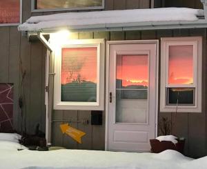 ein Haus mit zwei Fenstern und einer Tür mit Schnee in der Unterkunft Halcyon Heights B&B/Inn in Homer