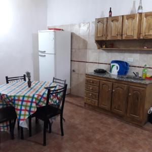 Una cocina con una mesa y un refrigerador blanco. en Departamentos ramallo, en Ramallo