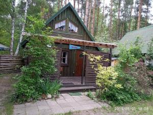 een kleine houten hut met een veranda in het bos bij Leśna Domek Dębki in Dębki