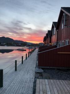 a dock next to a body of water at sunset at Ballstad Brygge Rorbu in Ballstad