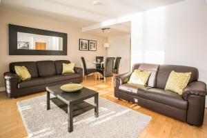 Una sala de estar con un sofá de cuero y una mesa. en Grand Canal Square Apartments, en Dublín