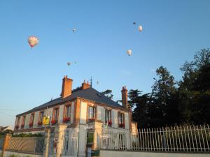 Logis Hotels Restaurants- Villa des Bordes في Cléry-Saint-André: منزل كبير وطائرات ورقية في السماء