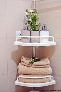 a white towel rack with towels and flowers in a bathroom at Wind Residences For Rent - Luiice in Tagaytay