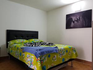 een slaapkamer met een bed met een kleurrijk dekbed bij New Cozy Apartment in the Poblado, San Lucas in Medellín